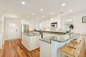 A modern kitchen with white cabinetry, granite countertops, and a built-in microwave.