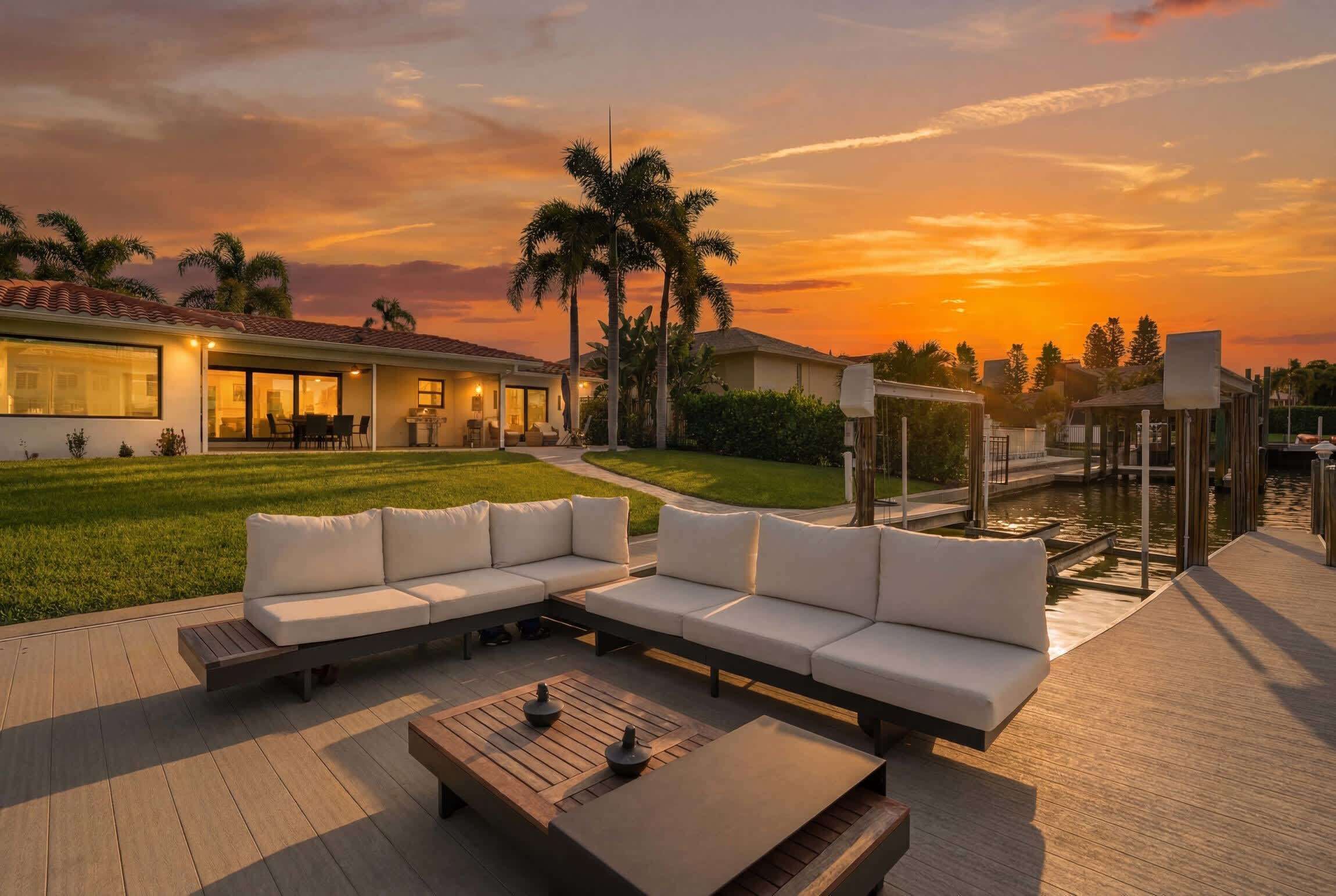 Uma área de estar moderna ao ar livre com sofá modular, mesa de centro de madeira e vista para a piscina ao pôr do sol.