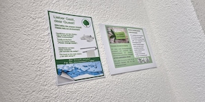 Two informational signs on a textured wall. One sign is in English and German, discussing towel usage and environmental care. The other sign is in German, explaining the concept of room cleaning and its benefits. - Melvi Hotel Goeppingen (Goeppingen)
