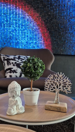A round wooden table with a Buddha statue, a potted plant, and a decorative tree sculpture. - Melvi Hotel Goeppingen (Goeppingen)