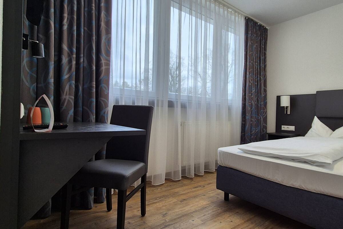 A hotel room with a bed, a desk, and a chair.