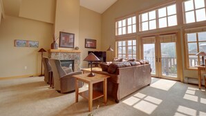 A spacious living room with a fireplace, comfortable seating, and large windows. - Largest Condo In Passage Point, Vaulted Ceilings, Huge Balcony - PP514 by Redawning (Copper Mountain)