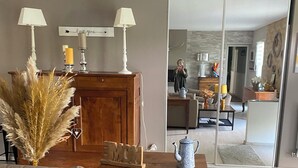 A modern living room with a sofa, a wooden cabinet, and a coffee table. There is a mirror reflecting the room, and a door leading to another area. - Spacious villa with private pool, summer kitchen, plancha barbecue near Bayonne (Mouguerre)