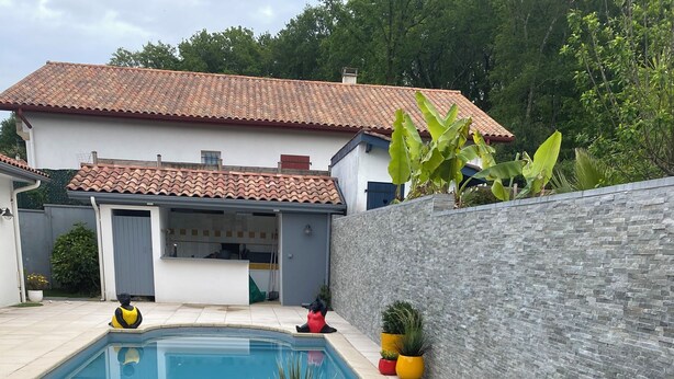 A swimming pool with a stone border, a metal ladder, and potted plants. - Spacious villa with private pool, summer kitchen, plancha barbecue near Bayonne (Mouguerre)