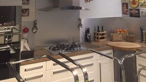 A kitchen with three pendant lights, a gas stove, and a wall with various brand logos. - Spacious villa with private pool, summer kitchen, plancha barbecue near Bayonne (Mouguerre)