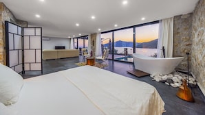 A modern bedroom with a large bed, a sitting area with a view of the sea, and a bathtub. - Villa Nana, A Modern 1 Bedroom Property in Komurluk (Antalya)