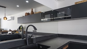 A modern kitchen with a black countertop, stainless steel appliances, and a sleek faucet. - Villa Nana, A Modern 1 Bedroom Property in Komurluk (Antalya)