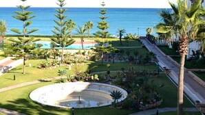 A landscaped garden with a circular fountain, palm trees, and a pool area. - Residence Marina Beach Mdiq 4881 (Mdiq)