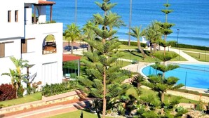 A resort with a pool, palm trees, and a view of the ocean. - Residence Marina Beach Mdiq 4881 (Mdiq)