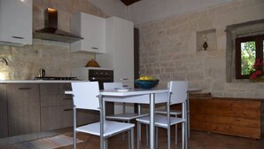 Una cocina moderna con armarios blancos, una estufa a gas y un frutero sobre la mesa.