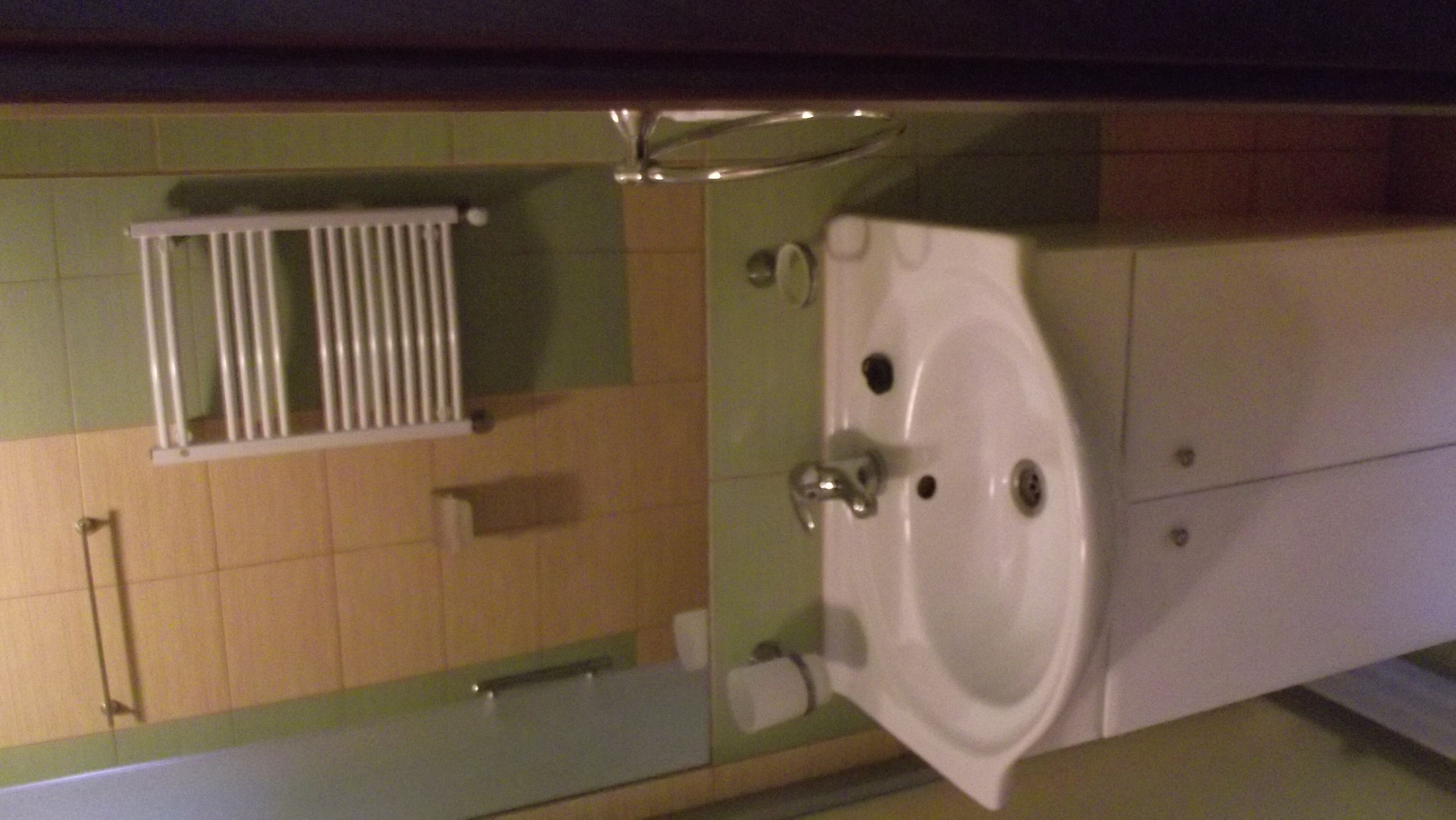A bathroom with a white sink, mirror, and a towel rack.