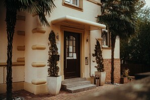 A building entrance with a dark door, steps, and a sign above the door. - CityWorld (Heidelberg)