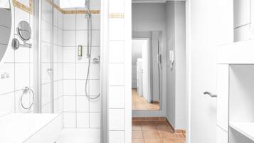 A modern bathroom with a walk-in shower, a vanity with a mirror, and a toilet.