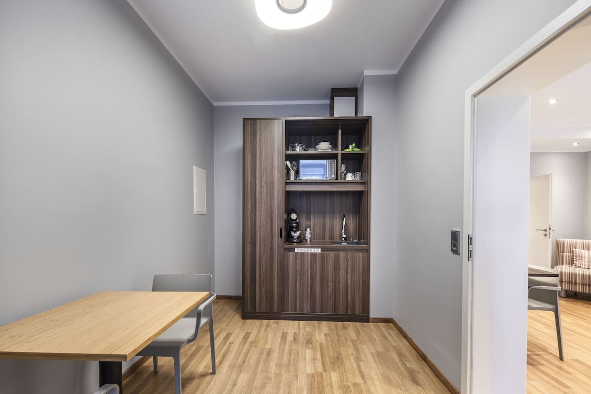 Cocina compacta con microondas integrado, lavamanos y armarios.