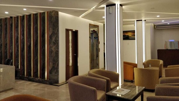 A modern hotel lobby with a reception desk, seating area, and a large pillar. - Hotel Zakaria International (Dhaka)