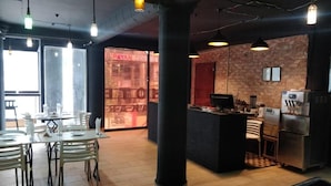 A restaurant with a bar area, tables, chairs, and a counter with a refrigerator. - Hotel Zakaria International (Dhaka)