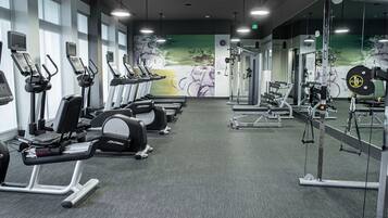 A gym with treadmills, weight machines, and a mirrored wall.