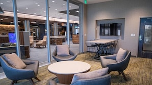 A modern lounge area with comfortable seating, a round table, and a large screen. - Courtyard by Marriott Greenville Mauldin (Greenville)