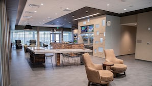 A modern hotel lobby with a bar area, seating, and a large window providing natural light. - Courtyard by Marriott Greenville Mauldin (Greenville)