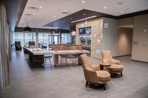 A modern hotel lobby with a bar area, seating, and a large window providing natural light.