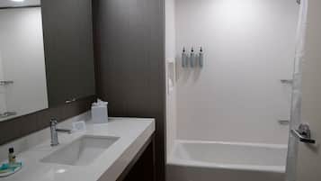 A modern bathroom with two sinks, a large mirror, and a bathtub.