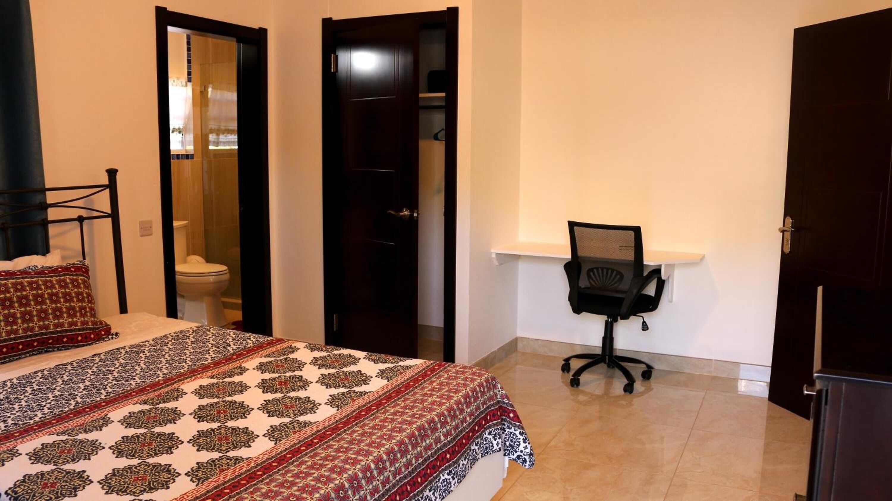 A bedroom with a bed, a desk, and a chair.