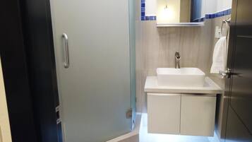 Un baño con un lavabo blanco, un espejo encima y una toalla colgada en un perchero.