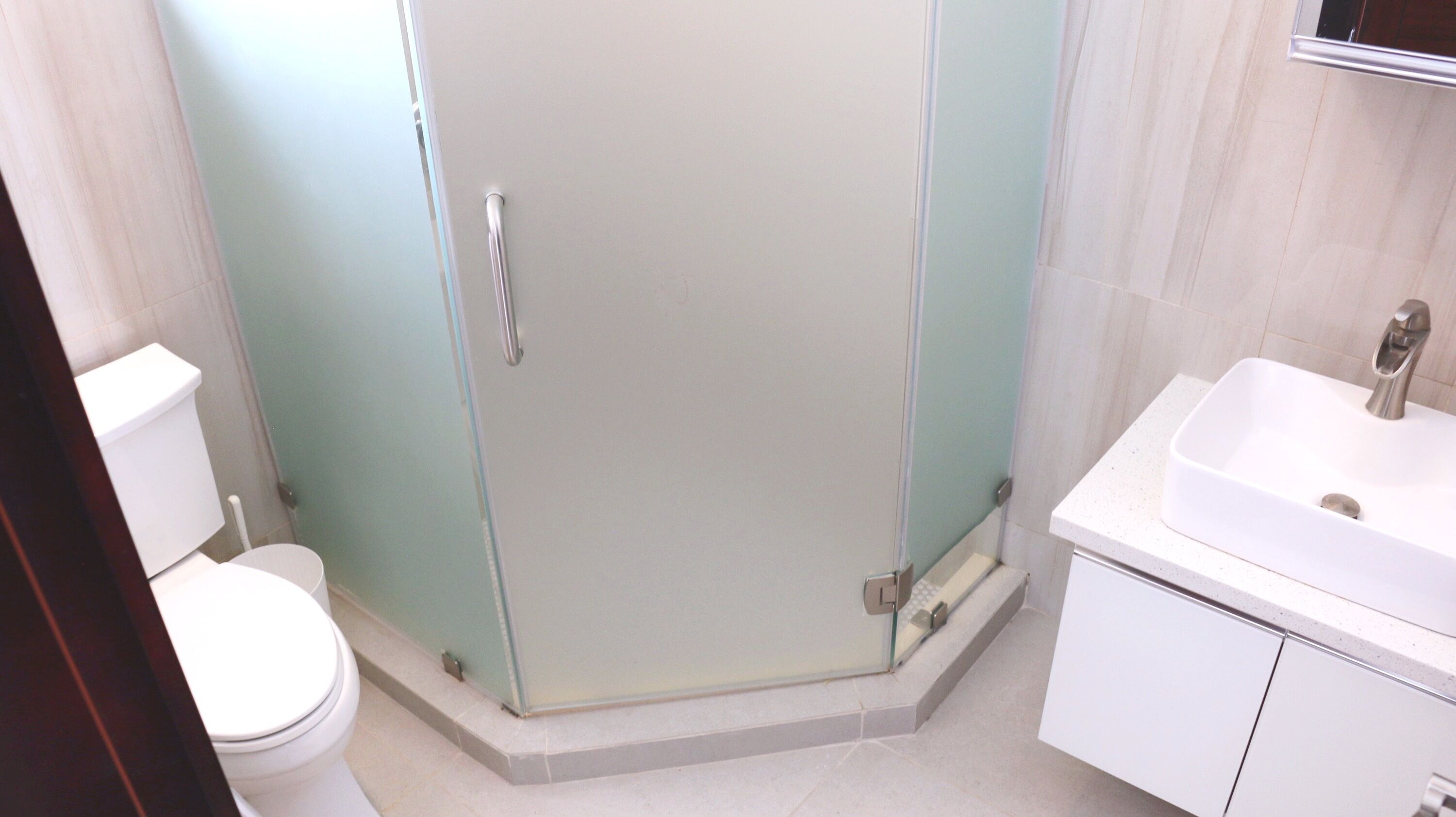 Ein Badezimmer mit Duschkabine, Waschbecken in Weiß und Toilette.