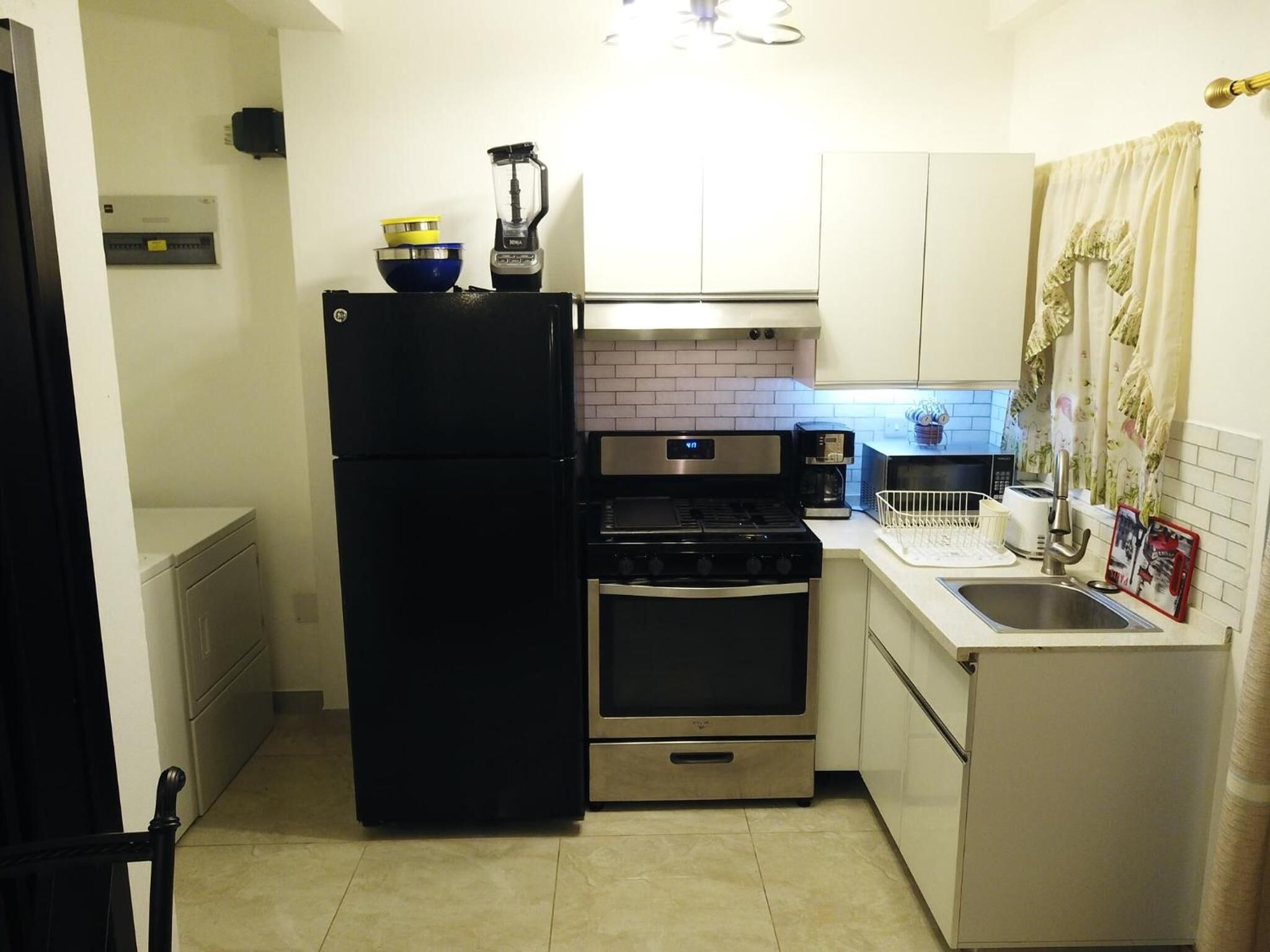 Una cocina compacta con un refrigerador negro, horno de acero inoxidable y microondas.