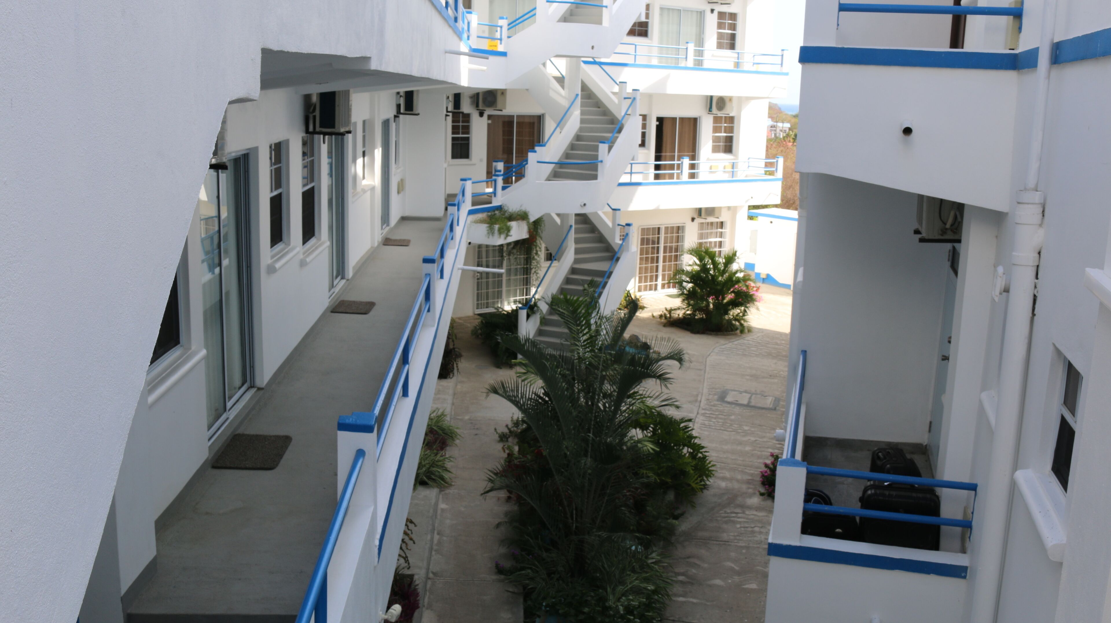 A multi-level building with a central staircase, balconies, and a courtyard with plants.