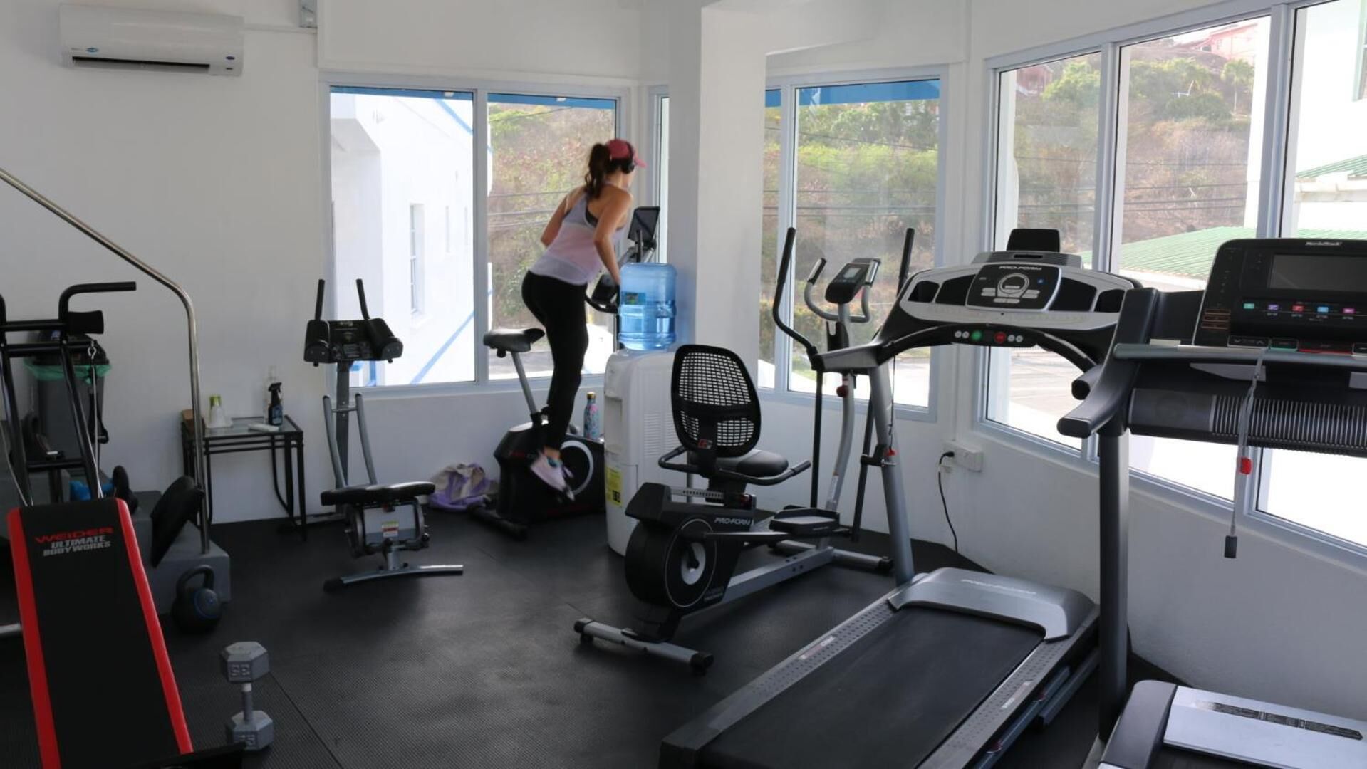 A home gym with various exercise equipment including treadmills, a stationary bike, and weight machines.