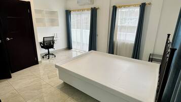 A spacious bedroom with a large bed, a desk, and a chair.