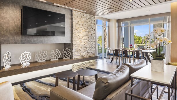 Una sala moderna con pared de piedra, un televisor de pantalla plana, sofás de cuero y un comedor con luz natural.