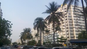A multi-story building with a modern architectural design, featuring balconies and air conditioning units.