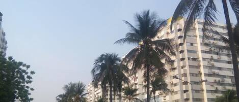 A multi-story building with a modern architectural design, featuring balconies and air conditioning units.