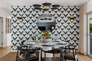 A dining area with a chevron-patterned wall, a central table with chairs, and a decorative bowl with flowers.