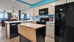 A modern kitchen with a central island, black appliances, and a view of the outdoors.