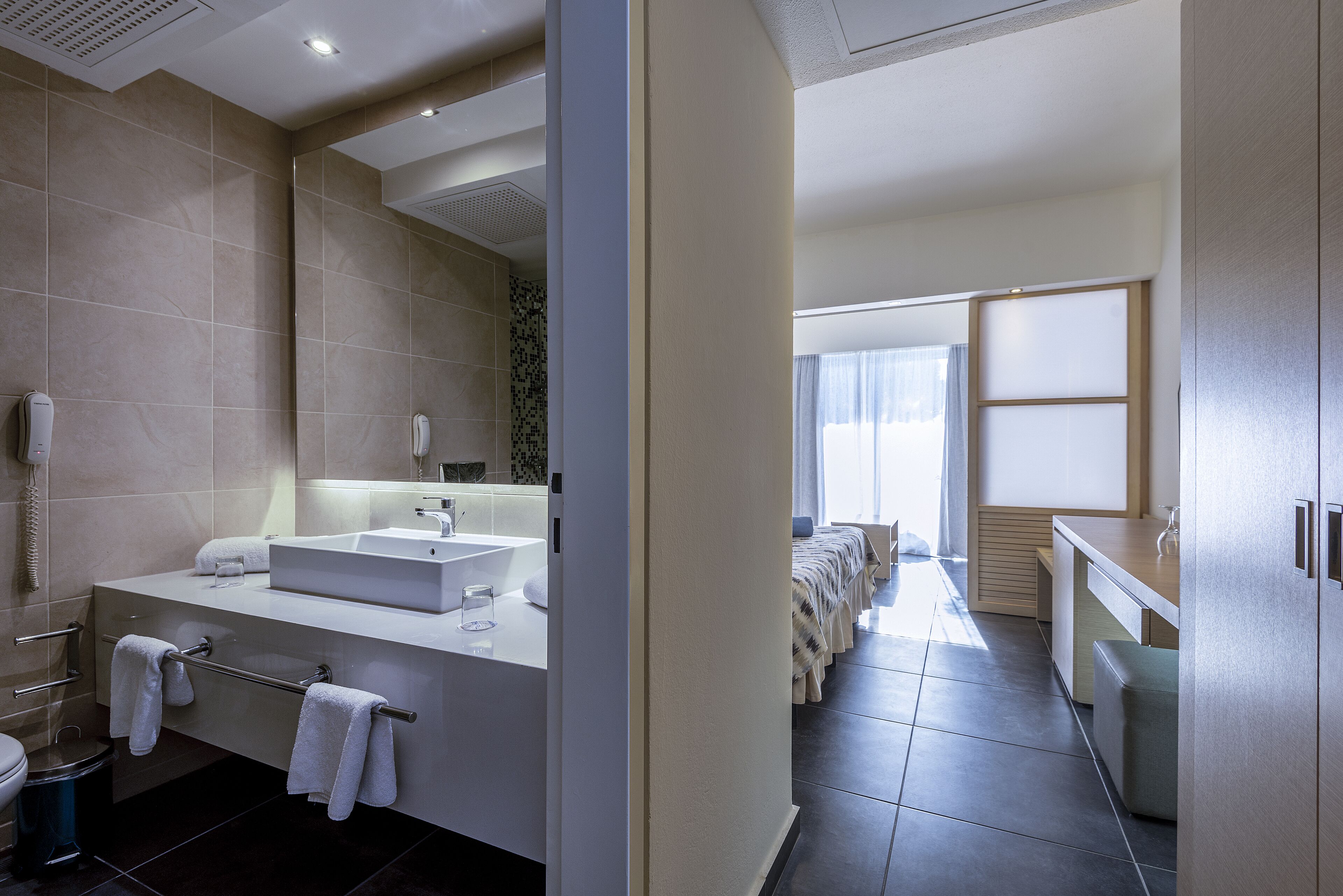 Un baño moderno con un lavamanos grande, espejo y toallero.