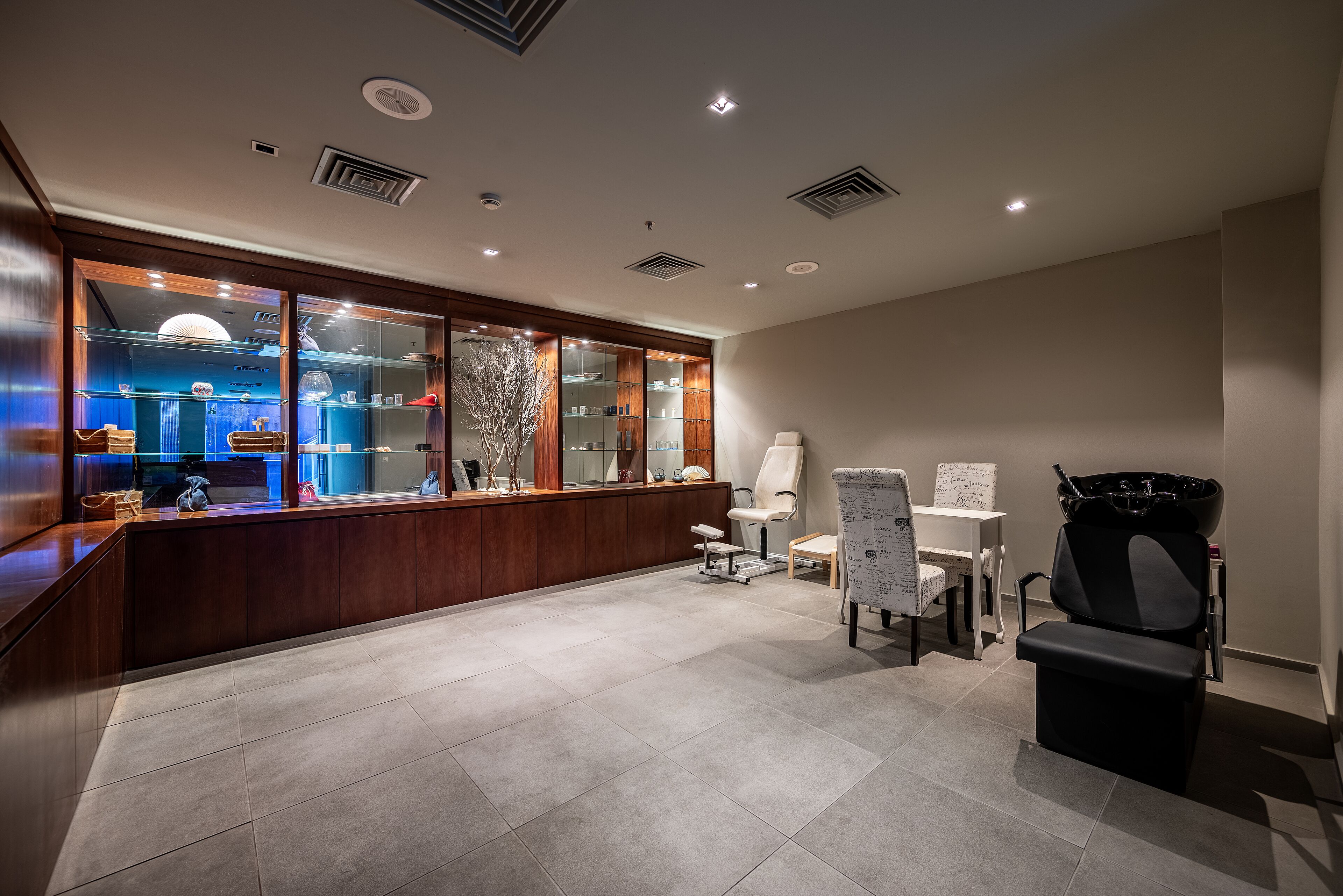 Zona de recepción con mostrador de madera, vitrinas de vidrio y disposición de asientos.