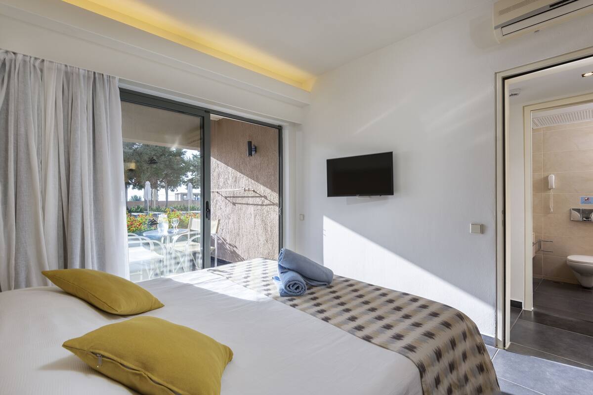 Een hotelkamer met een bed, televisie, balkon en badkamer.
