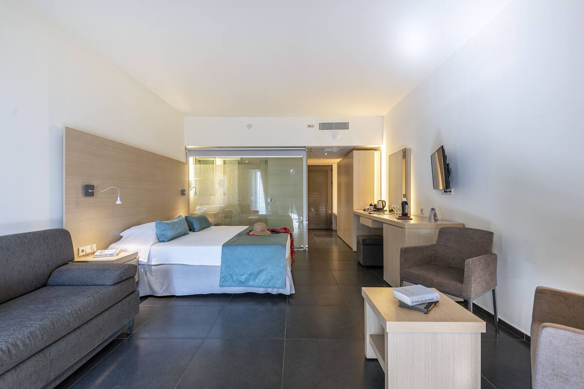 Een moderne hotelkamer met een bed, een bank, een bureau en een televisie.