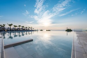 Una piscina al aire libre, sombrillas, sillones reclinables de piscina