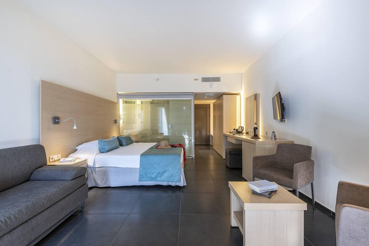 Een moderne hotelkamer met een bed, een bank, een bureau en een televisie.