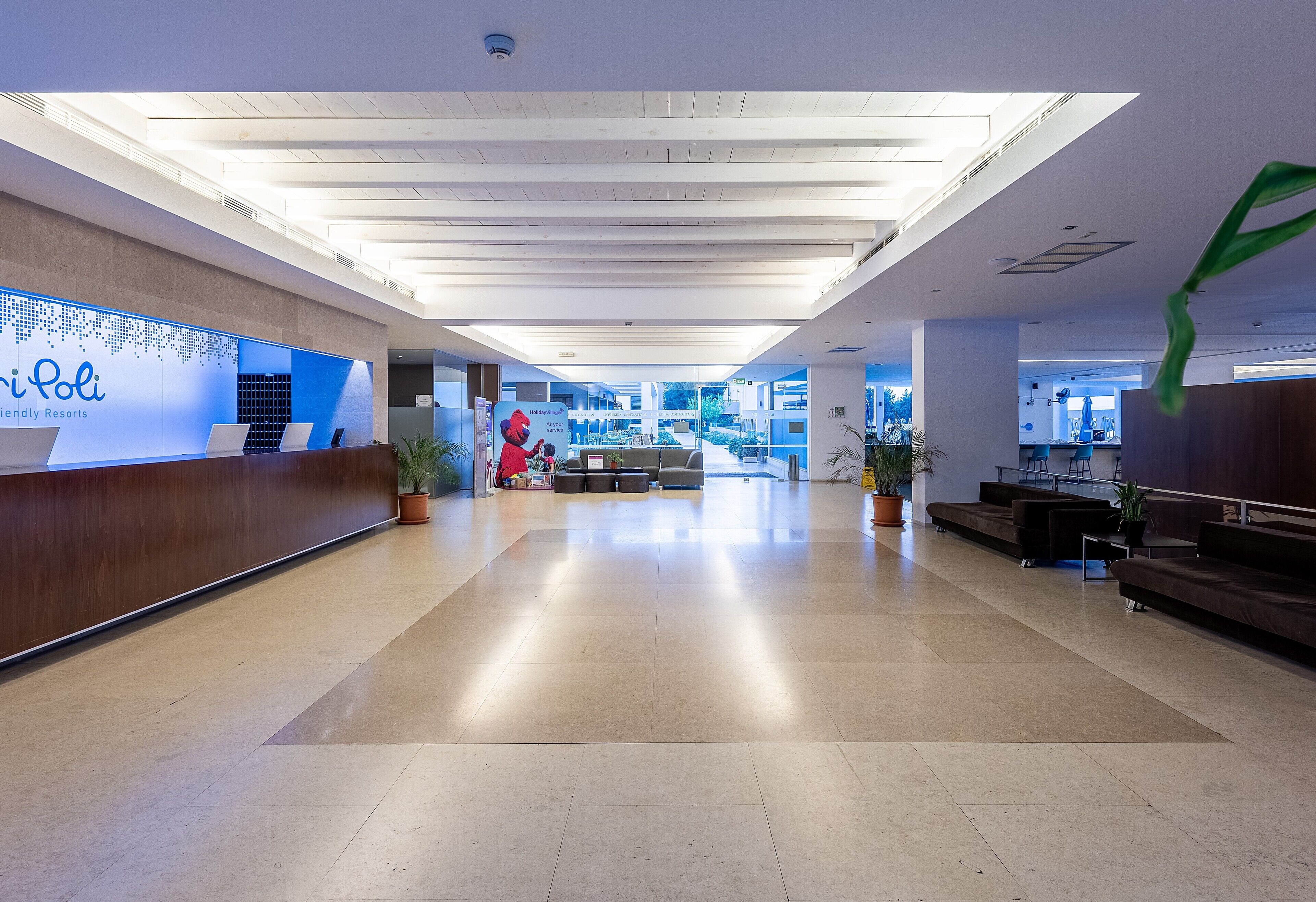 Un vestíbulo amplio con una recepción, zonas de estar y vistas al complejo hotelero.