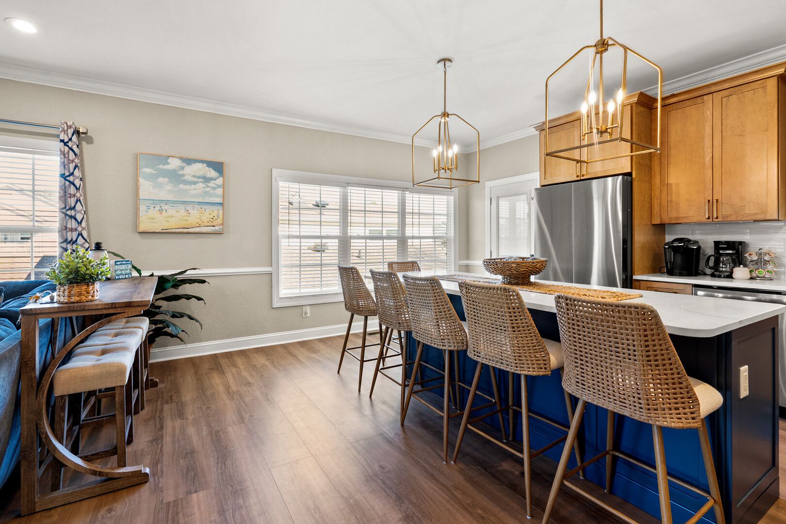 A modern kitchen with a central island, bar stools, and a hanging light fixture.