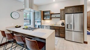 A modern kitchen with a central island, stainless steel appliances, and wooden cabinets.