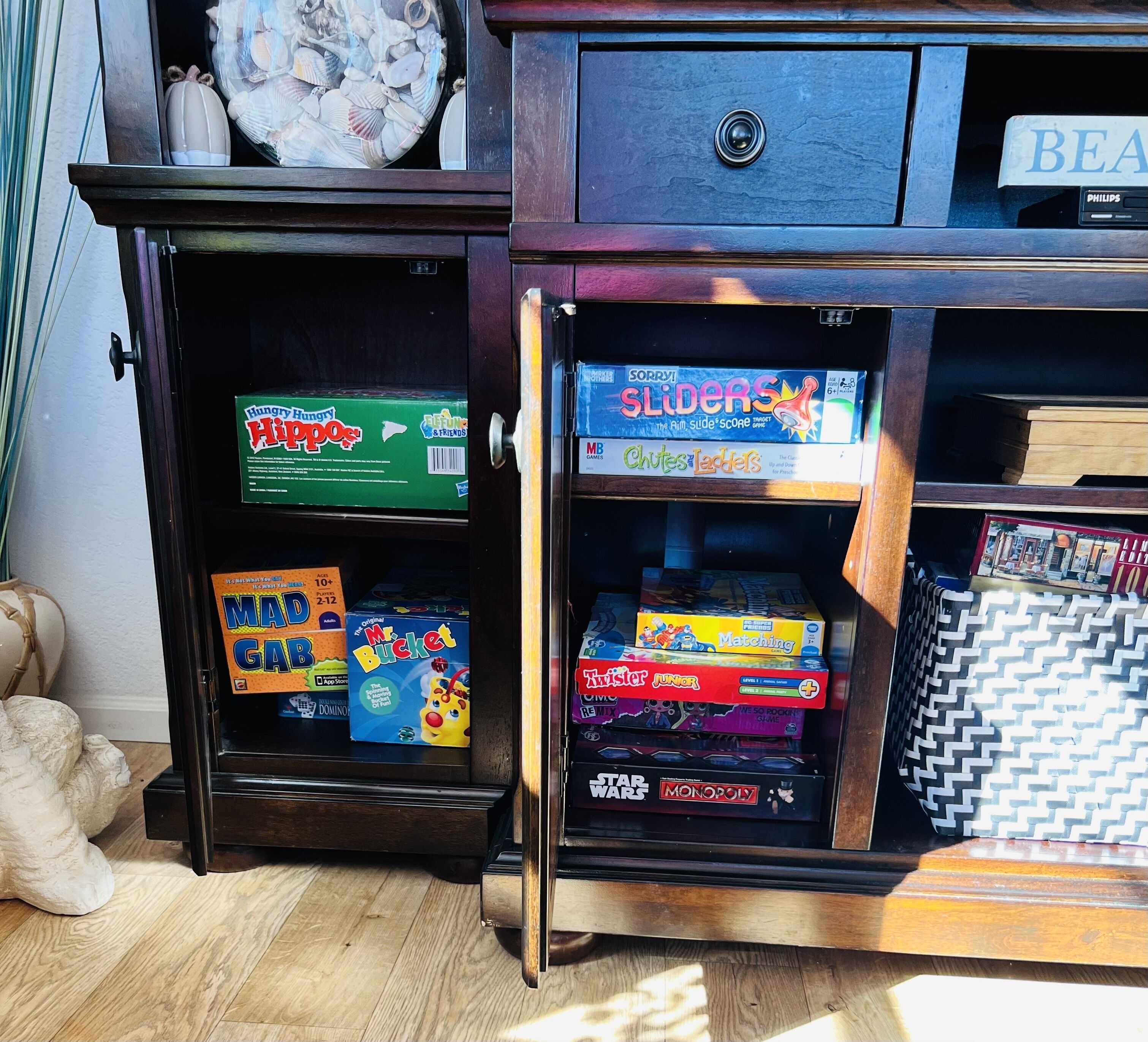 Een houten kast met meerdere planken vol met diverse bordspellen.