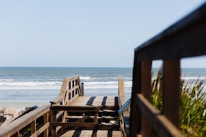 A wooden pier leading to a beach with waves in the background.
