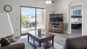 Een moderne woonkamer met een eettafel, bank, televisie en balkon met tuinmeubilair.