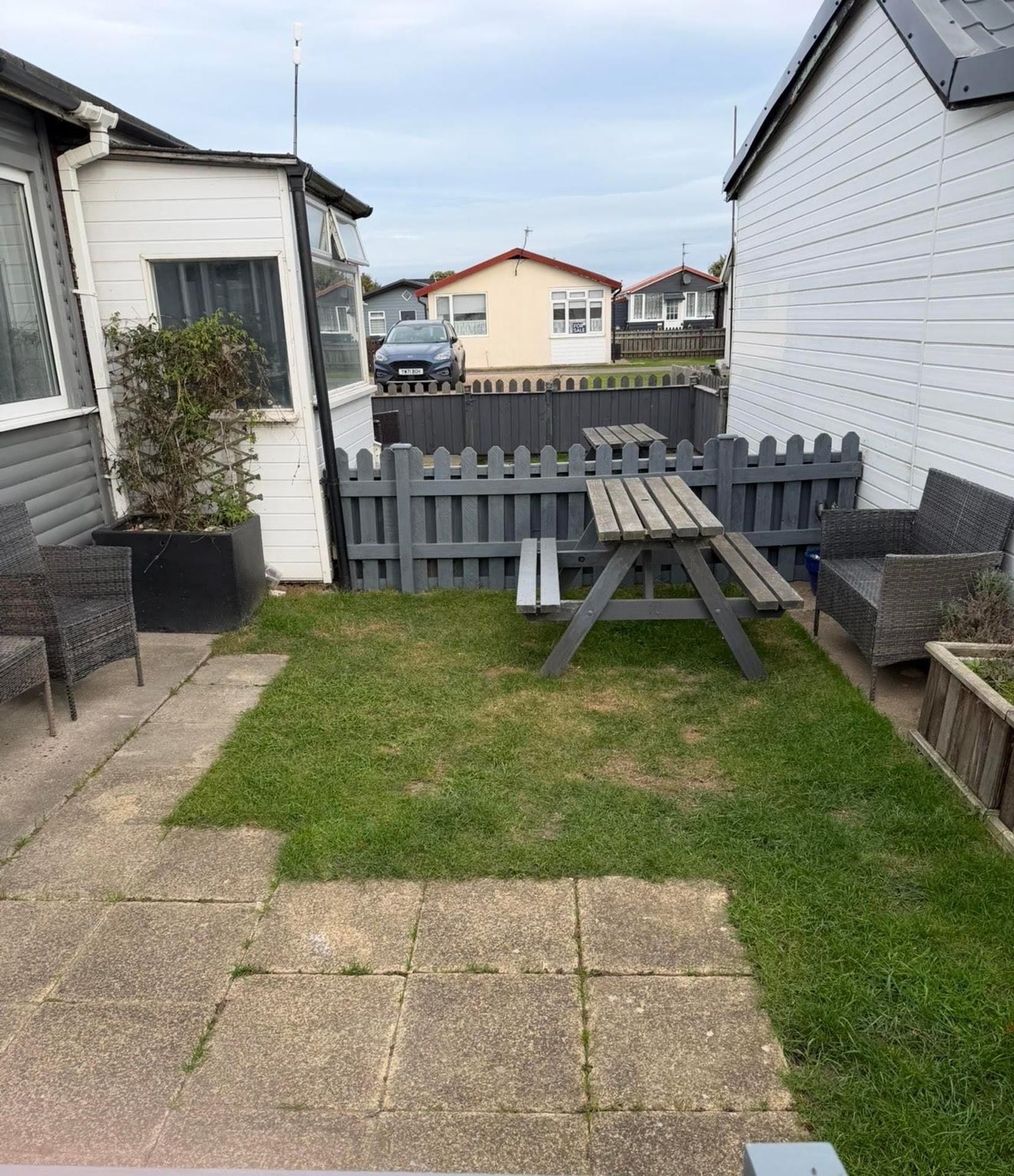 A backyard with a wooden fence, a picnic table, and outdoor furniture.